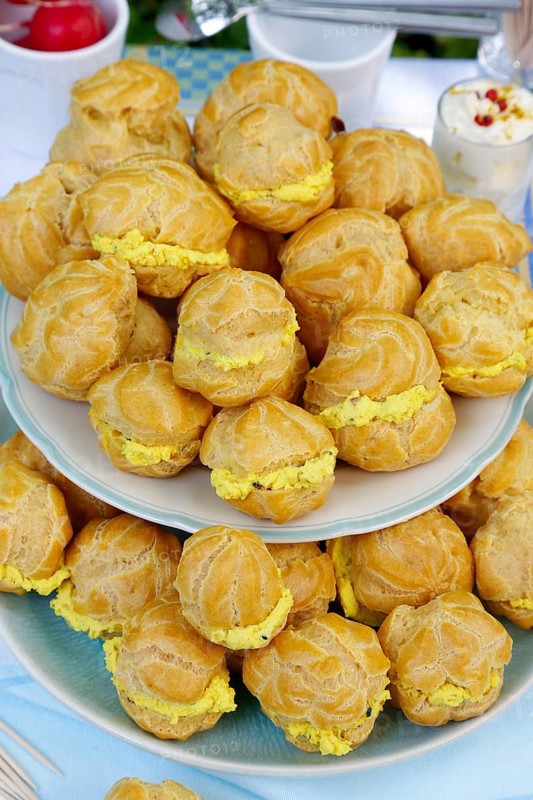 Swabian cuisine, mini cream puffs filled with goat's cream cheese, cream cheese éclairs, profiterole arranged on plate, shortbread, oven cakes, choux pastry, pastry, hearty, salty, choux pastry, baked, from the oven, vegetarian, bake, from the oven, typical Swabian reinterpreted, party pastry, finger food, appetisers for on the go, traditional cuisine reinterpreted, food photography, Germany, Europe