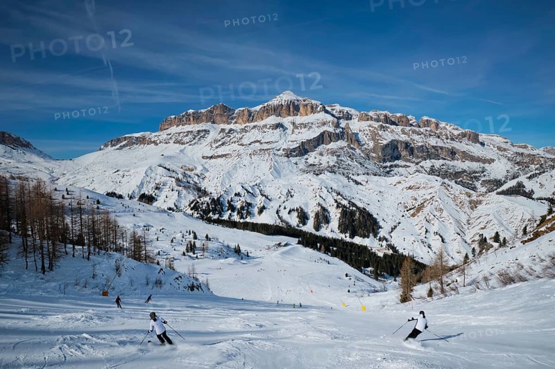View of a ski resort piste with people skiing in Dolomites in Italy. Ski area Arabba. Arabba, Italy, Europe