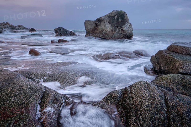 Rocks on beach of fjord of Norwegian sea in winter on sunset. Utakliev beach, Lofoten islands, Norway, Europe