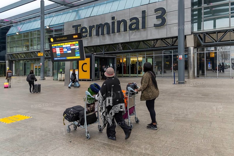Passengers with luggage outside Terminal 3 building, London Heathrow Airport, England, UK