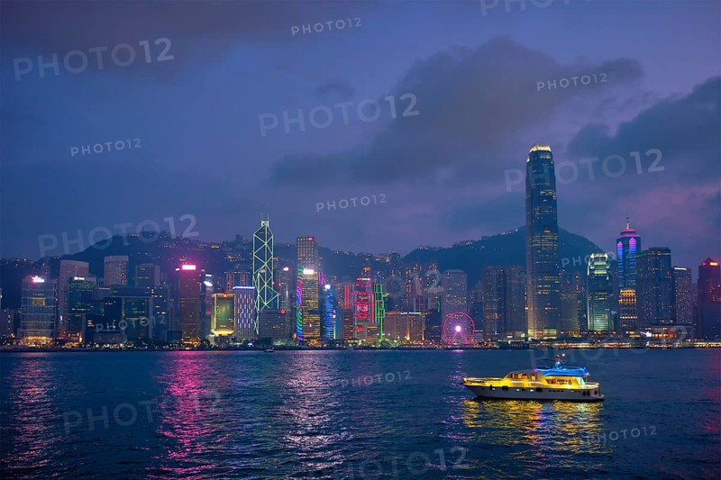 Hong Kong skyline cityscape downtown skyscrapers over Victoria Harbour in the evening illuminated with tourist boat ferries, Hong Kong, China, Asia