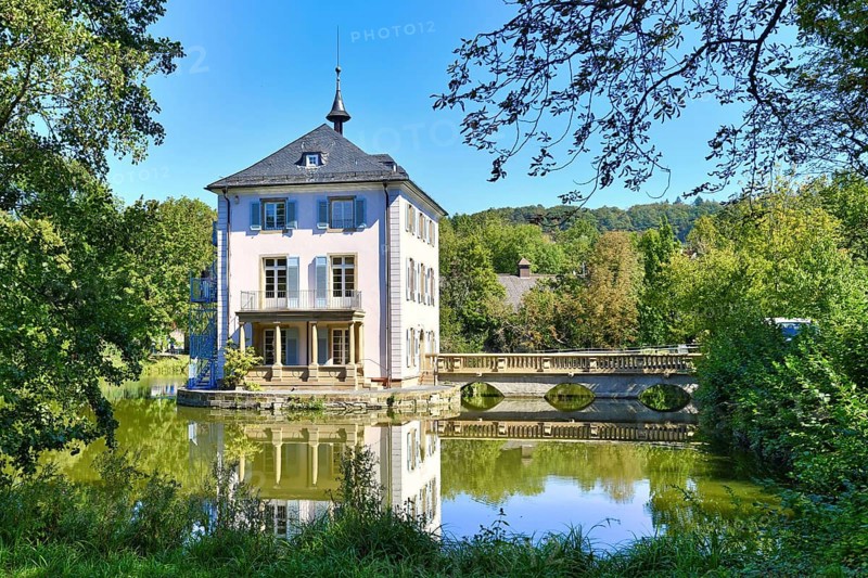 Small cultural heritage baroque castle building called Trappenseeschloss in middle of lake in Heilbronn in Germany on sunny day