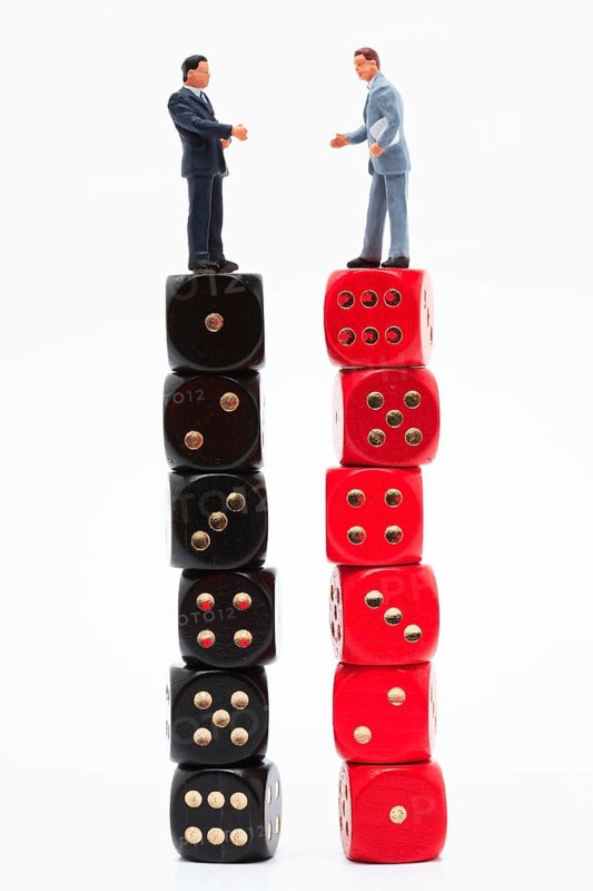 Symbol photo, two men (figure) standing perplexed on a stack of dice each showing the values 1 to 6 ascending and descending
