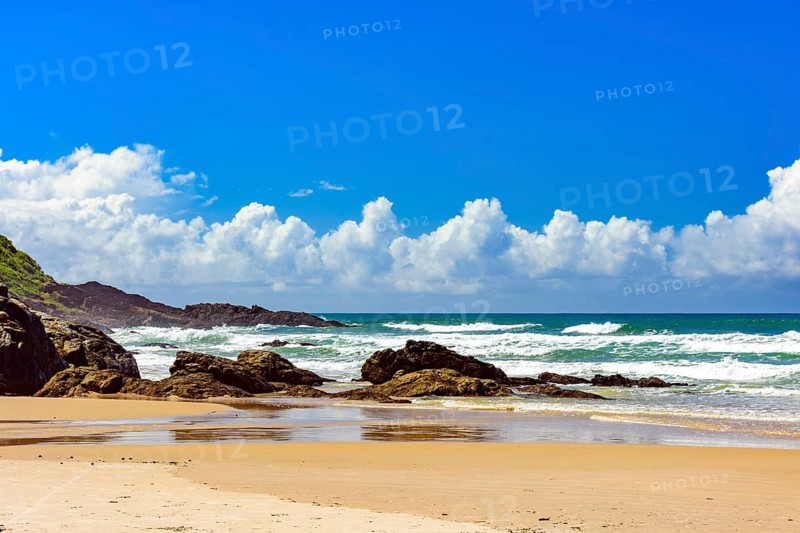 Beach with waves breaking against the rocks on a sunny day in the town of Serra Grande on the coast of Bahia