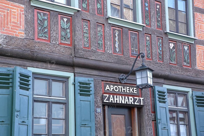 Historic half-timbered house with flowers as wall painting and wood carving with inscription Pharmacy and dentist, Babenhausen, Hesse, Germany, Europe