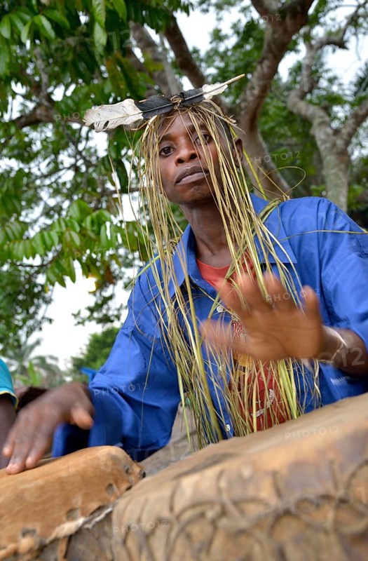Musician with a headdress made of bast and a feather, playing drums, Nkala, Bandundu Province, Democratic Republic of the Congo