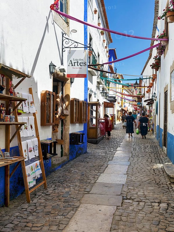 Picturesque alley with shops and pedestrians, tourists in the medieval village of Óbidos, Portugal, Europe