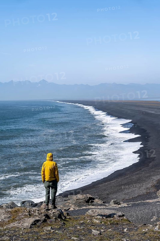 Tourist looking over long black sand beach, Reynisfjara Beach, South Iceland, Iceland, Europe