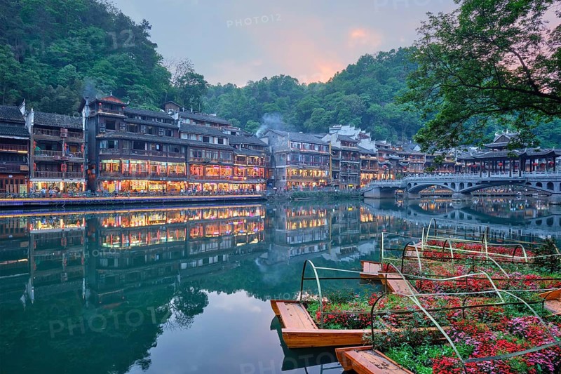 Chinese tourist attraction destination, Feng Huang Ancient Town (Phoenix Ancient Town) on Tuo Jiang River with bridge illuminated at night. Hunan Province, China, Asia