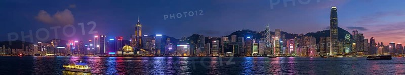 Panorama of Hong Kong skyline cityscape downtown skyscrapers over Victoria Harbour in the evening illuminated tourist boats and ferries, Hong Kong, China, Asia