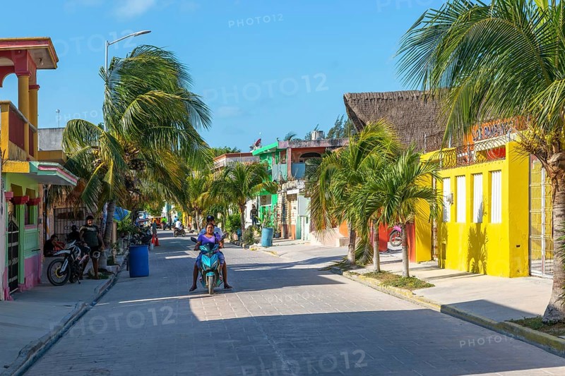 Palm trees motorcycles colourful buildings on quiet village road, Celestun, Yucatan, Mexico, Central America