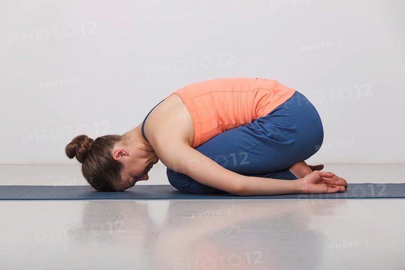 Beautiful sporty fit yogini woman practices yoga asana balasana (child's pose), resting pose or counter asana for many asanas in studio