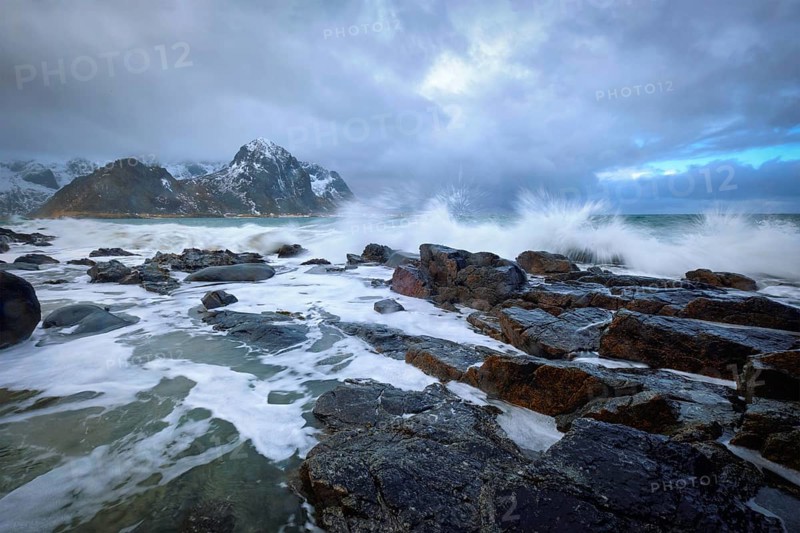 Waves crushing on rocks on rocky coast of fjord of Norwegian sea in winter. Lofoten islands, Norway, Europe