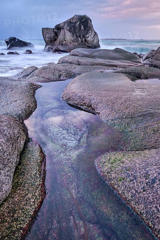 Rocks on beach of fjord of Norwegian sea in winteron sunset. Utakliev beach, Lofoten islands, Norway, Europe
