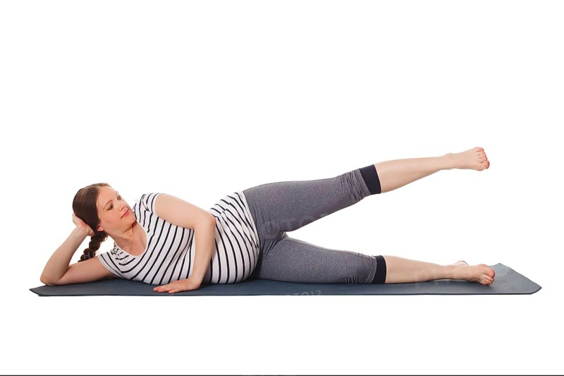 Pregnancy yoga exercise, pregnant woman doing yoga asana Vishnuasana Easy Side Reclining Leg Lift Pose isolated on white background