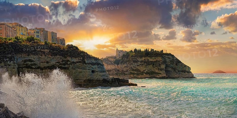 Coastal view of the old town of Tropea on sandstone cliffs and the medieval church Santuario di Santa Maria dell Isola at sunset with the Strompoli volcano in the distance, Tropea, Vibo Valentia, Calabria, Southern Italy, Italy, Europe