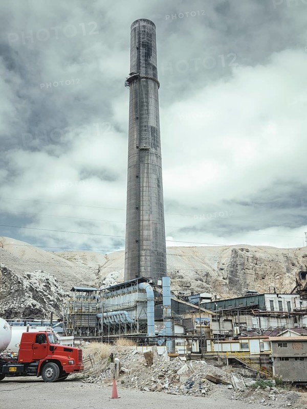 Chimney of the smelter, in the foreground a spoil heap contaminated with heavy metal residues, La Oroya, Peru, South America