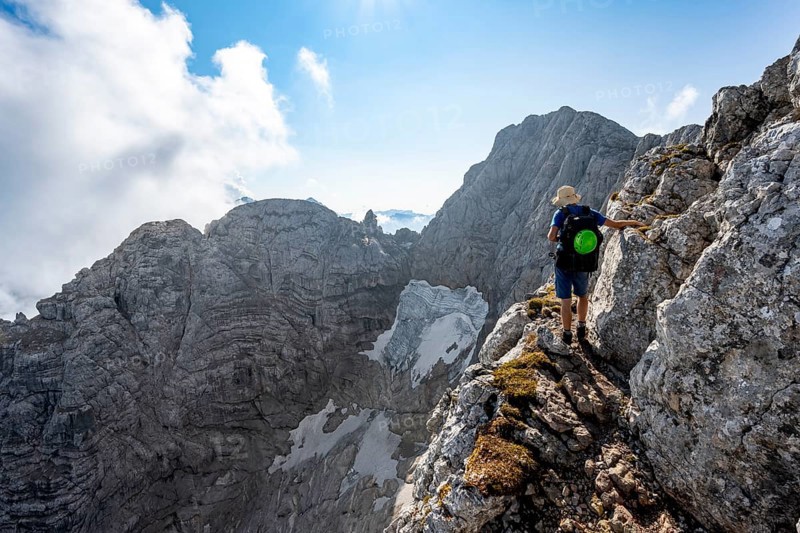 Mountaineer on a rocky narrow mountain path, view of rock faces with blue ice glacier and summit of the Hochkalter, mountain tour on the Hochkalter, Berchtesgaden Alps, Bavaria, Germany, Europe