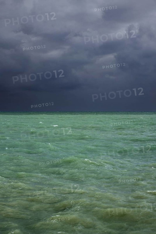 Dark rain clouds over emerald coloured sea water