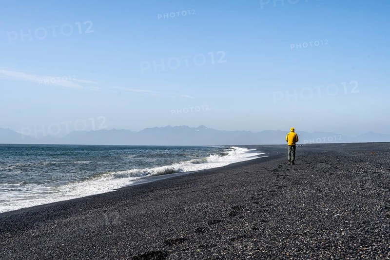 Tourist walking on a long black sand beach, Reynisfjara Beach, South Iceland, Iceland, Europe