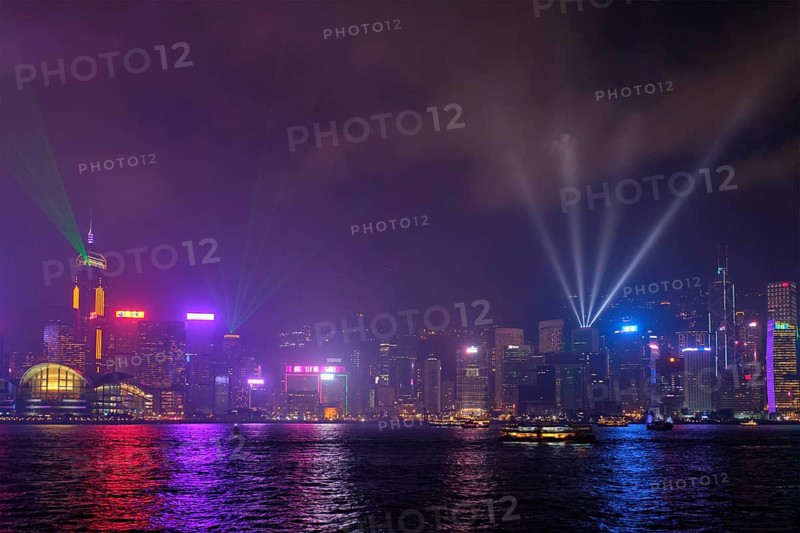 Hong Kong skyline cityscape downtown skyscrapers over Victoria Harbour in the evening illuminated with lasers with tourist boat ferries, Hong Kong, China, Asia