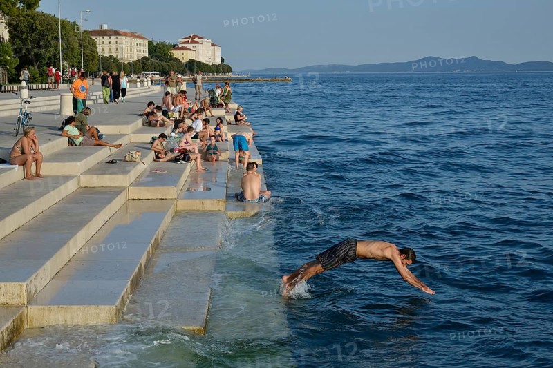Visitors basking in the evening sun at the Sea Organ by architect Nikola Bašic, Zadar, Dalmatia, Croatia, Europe