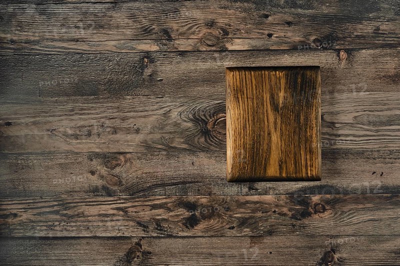 A handcrafted wooden cutting board rests on a rustic wooden table, showcasing the grain\'s beauty and warmth in natural lighting, perfect for culinary preparations and kitchen aesthetics
