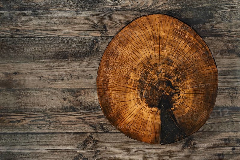 A rustic log slice for chopping food showcases its natural texture and growth rings while lying on a weathered wooden tabletop