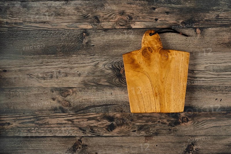 A beautifully crafted wooden cutting board rests on a rustic wooden countertop, showcasing its natural grain and warm tone. Ideal for culinary enthusiasts and kitchen decor inspiration