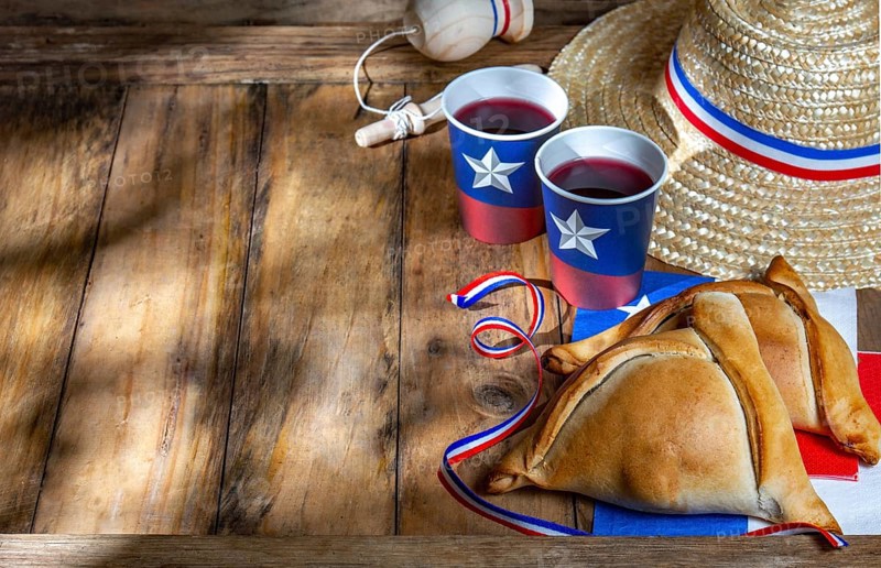 Food Photography, Chilean independence day concept. fiestas patrias. Tipical baked empanadas, wine or chicha, fat and play emboque. Decoration for 18 september party day, wooden background, top view