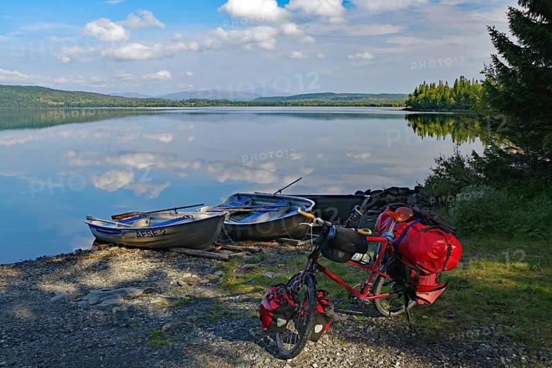 A lake with docked boats, a bicycle standing on the shore, surrounded by trees and under a cloudy sky, Viken, Störlien, Jämtland, Sweden, Europe