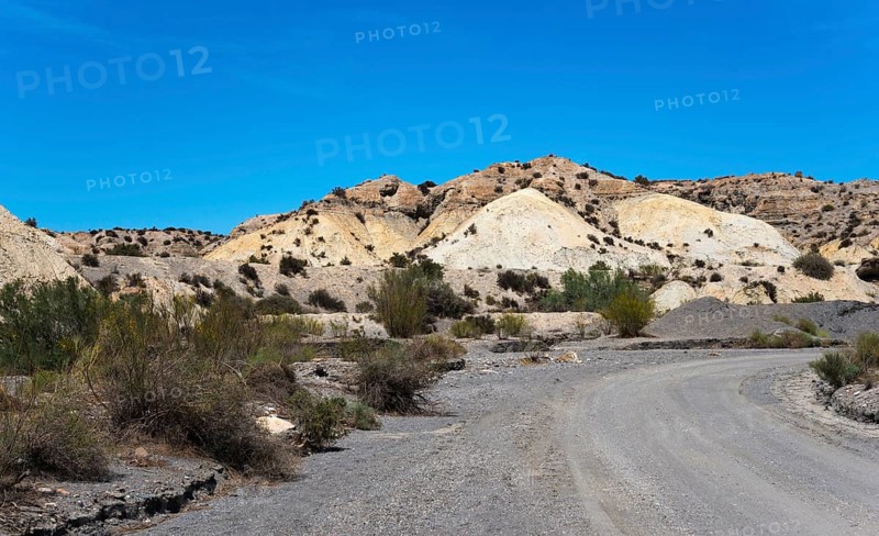 Dusty path through a dry, rocky desert landscape under a clear blue sky, Tabernas Desert, Desierto de Tabernas, location of numerous films and westerns, Tabernas, Almeria, Andalusia, Spain, Europe