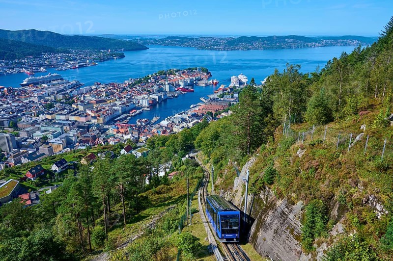 Panoramic view of Bergen with harbour on a clear day, cable car ascending the wooded mountain, Fløibanen mountain station, Bergen, Vestland, Norway, Europe