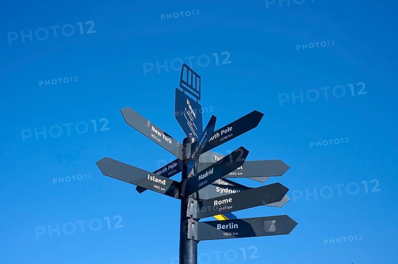 Black signpost against a blue sky with directions to various towns and destinations, Fløibanen mountain station, Bergen, Vestland, Norway, Europe