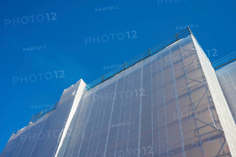 Shielding of a building by a tarpaulin attached to scaffolding against a clear blue sky, Bergen, Vestland, Norway, Europe