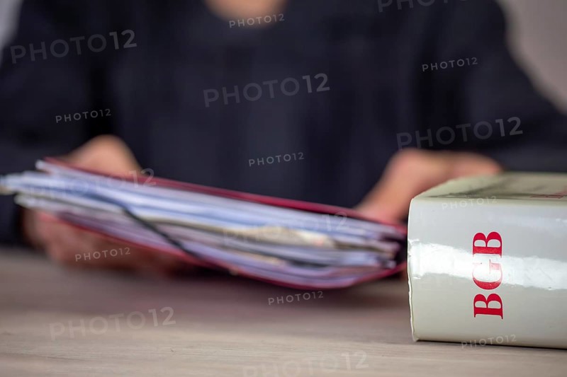 Symbolic image of a court hearing: close-up of a BGB (German Civil Code) and an implied judge with a briefcase