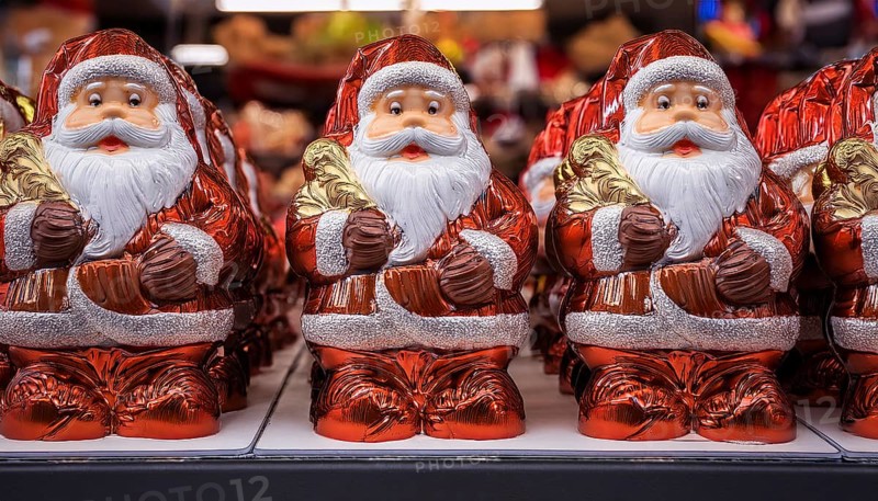 Symbol image for chocolate Santas wrapped in aluminium foil, cheerful looking Santas lined up on a shelf in a shop, AI-generated image, AI generated