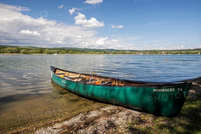 Green canoe on the shore of a lake with clear water and cloudy sky, quiet peaceful surroundings, Markelfingen, Markelfingerwinkel, Untersee, Lake Constance, Kreis Konstanz, Baden-Württemberg, Germany, Europe