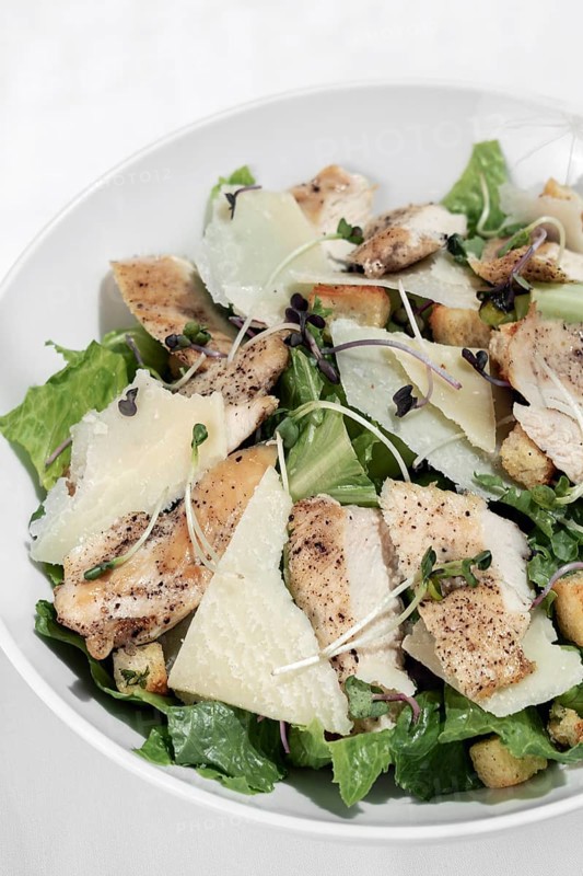 Organic chicken caesar salad with parmesan cheese and croutons on white table background