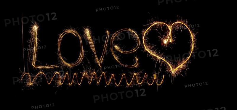 Inscription Love and heart of sparklers. Sparks of holiday lights on black background with heart and spiral