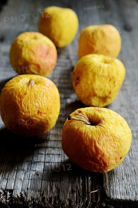 Wrinkled yellow apples on a wooden board