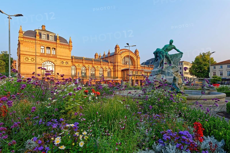 World Heritage Residence Ensemble Schwerin, railway station with richly decorated facades, surrounded by blooming flowers and an enchanting fountain with a statue in the foreground, Schwerin, Mecklenburg-Vorpommern, Germany, Europe