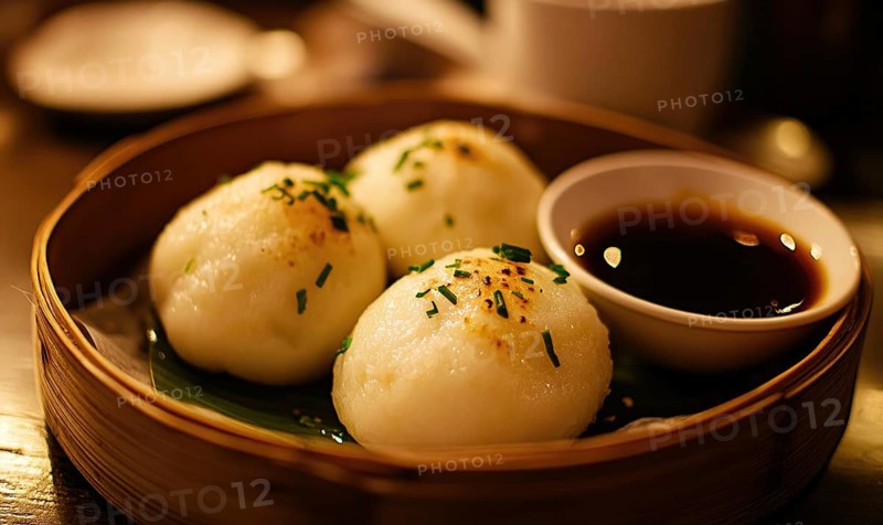 Three white dumplings with parsley on top sit in a bamboo basket. A small bowl of sauce is placed next to the dumplings AI generated
