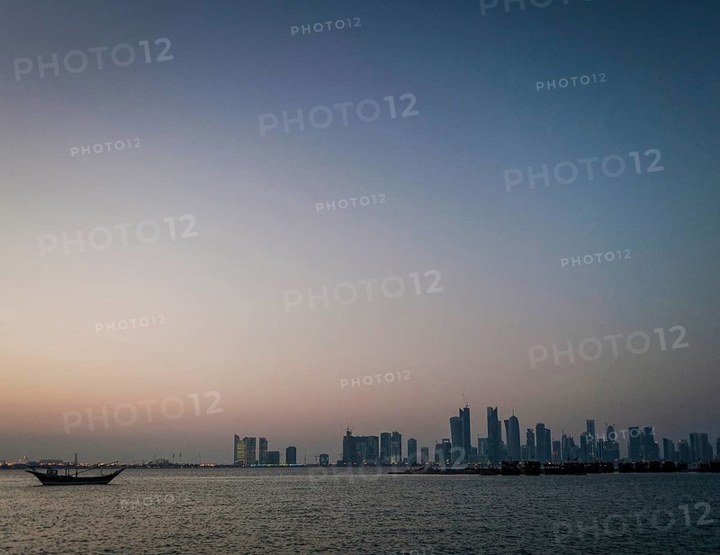 Doha city skyscrapers urban skyline view and dhow boat in qatar at sunset