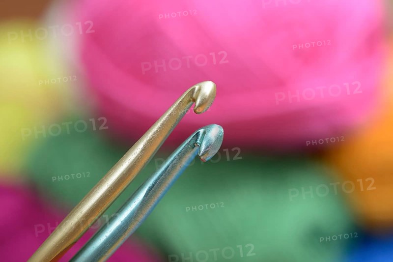 Two crochet hooks on a background of colorful wool