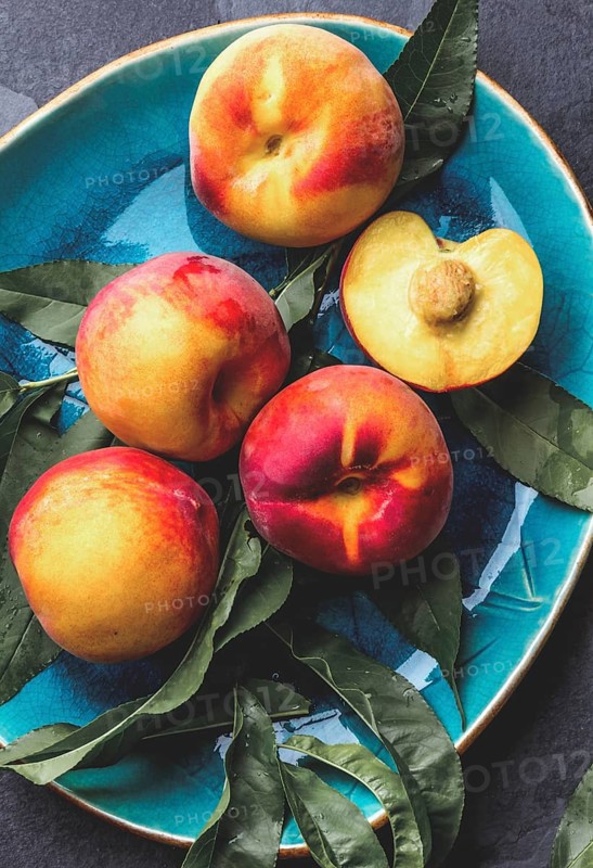 Food, Fresh ripe peach with peach tree leaves on blue plate, top view