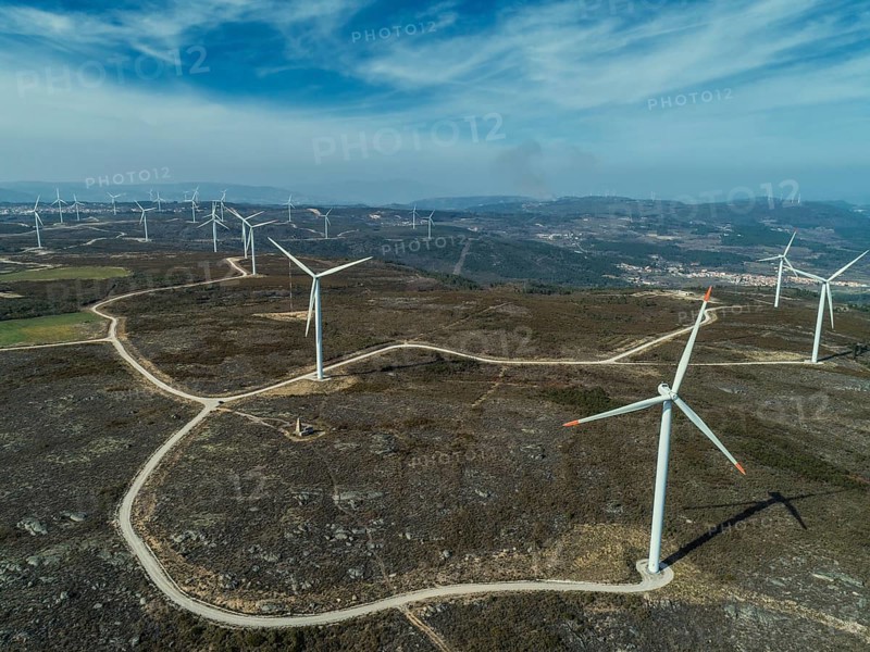 Aerial view of lot of windmills or wind turbine on wind farm in rotation to generate electricity energy
