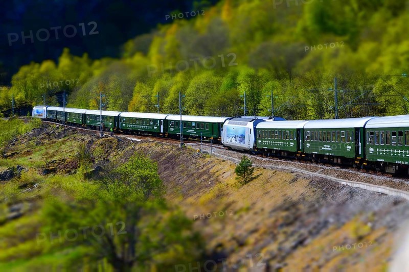 Flam, Norway, May 2015: train carriages of the Flamsbana (Flam Line) running through a green valley. Flam railway is a railway line between Myrdal and Flåm in Aurland, Norway, Europe