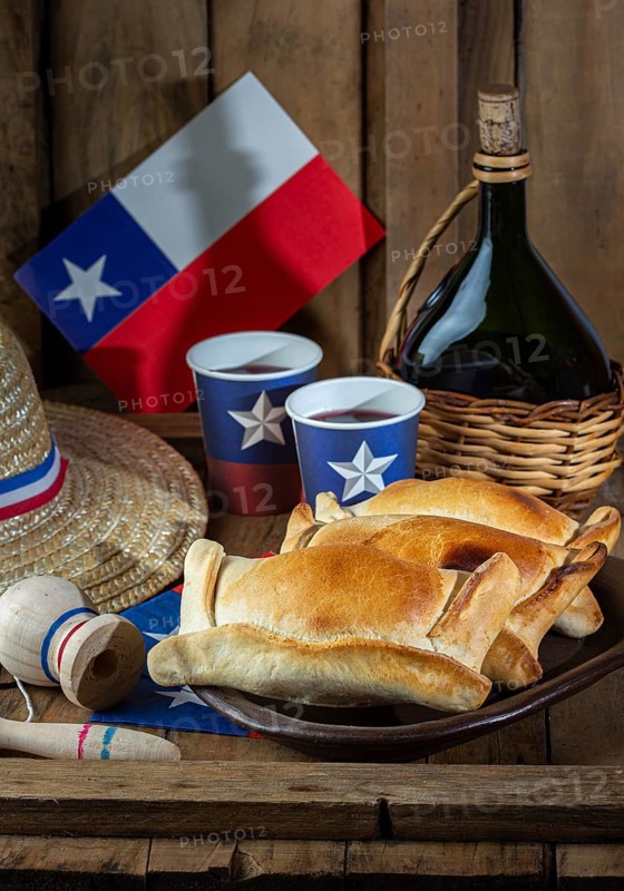 Food Photography, Chilean independence day concept. fiestas patrias. Tipical baked empanadas de pino, wine or chicha, hat and play emboque. Dish and drink on 18 September party, wooden background