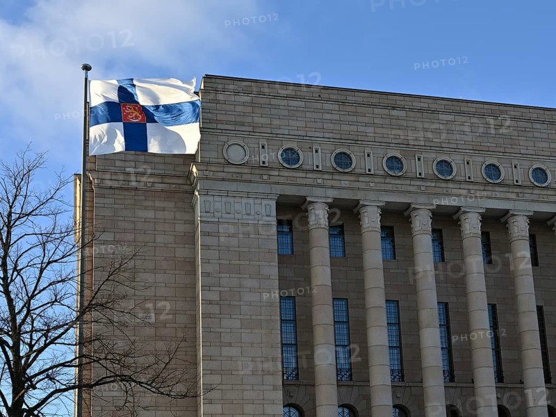 Waving Finnish flag and Finnish parliament building on Finnish Independence Day